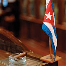 A Cuban flag and cigar in an ashtray